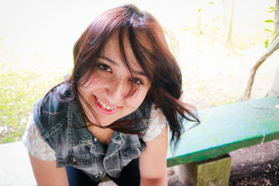 Portrait of smiling young woman sitting on bench