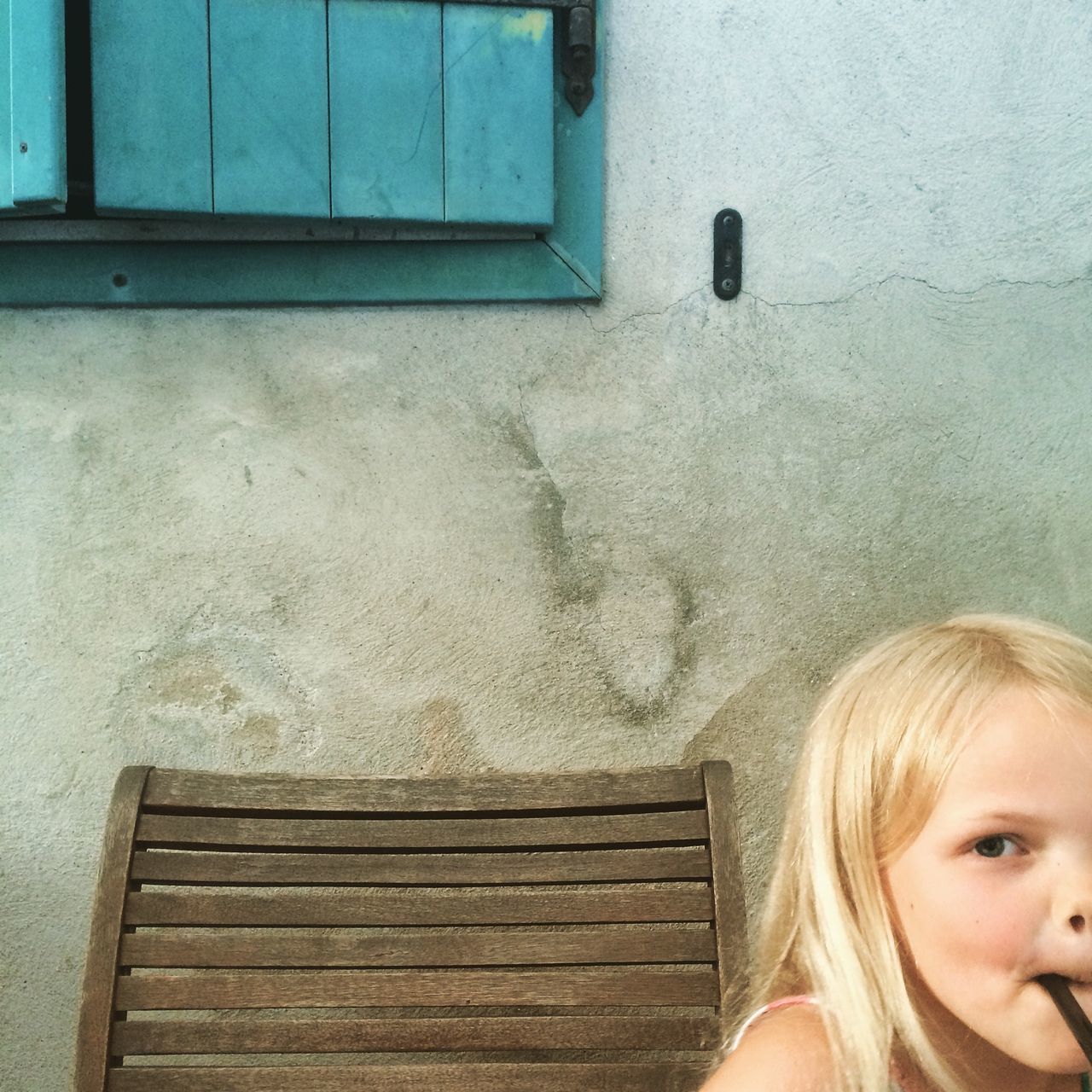 wall - building feature, built structure, childhood, wall, architecture, person, close-up, wood - material, front view, lifestyles, house, looking at camera, building exterior, door, headshot, wooden, day, outdoors