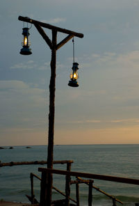 Lifeguard hut in sea against sky during sunset