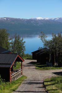 House by lake and buildings against sky