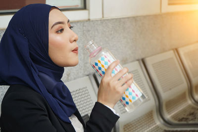 Side view of a young woman drinking glasses