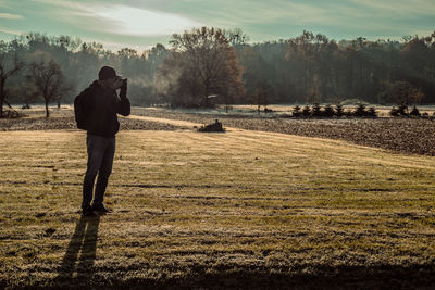 Full length of man photographing while standing on field