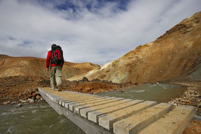 Hiker crossing wooden bridge in the icelandic highlands