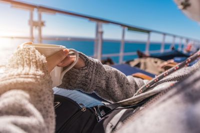 Midsection of woman having drink while sitting in boat