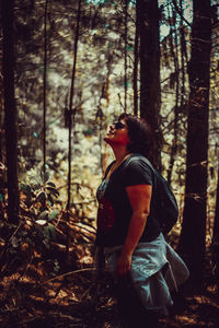 Side view of woman standing in forest