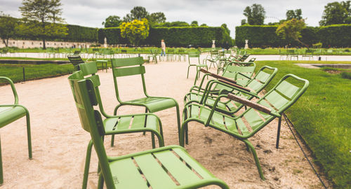 Empty chairs in park against sky