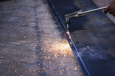 Cropped hand of welder welding metal in workshop