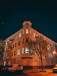 Illuminated building by street against sky at night