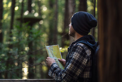 Midsection of man holding camera in forest