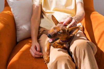 Mature woman sitting in chair with a small dog of the miniature pinscher breed