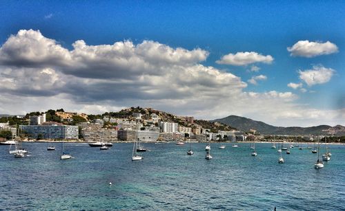 Boats in sea against cloudy sky