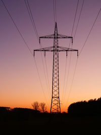 Low angle view of silhouette electricity pylon on field against romantic sky