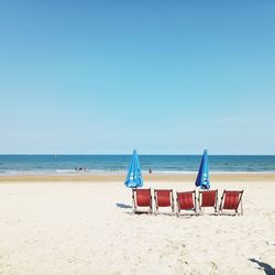 Chairs on beach against clear sky