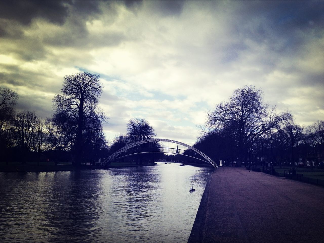 tree, sky, architecture, built structure, cloud - sky, water, cloudy, bridge - man made structure, river, bare tree, connection, cloud, building exterior, waterfront, nature, incidental people, park - man made space, travel destinations, overcast, bridge