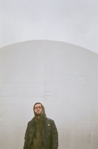 Portrait of young man standing against wall