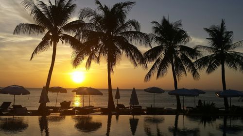 Infinity pool by sea against sky at sunset