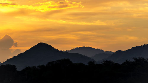 Scenic view of silhouette mountains against orange sky