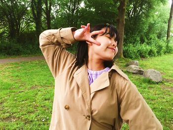 Portrait of young woman with a peace sign standing on field