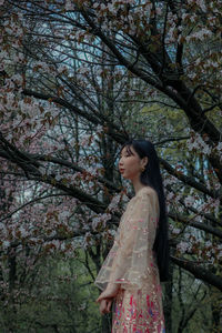 Young woman standing against trees