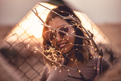 Portrait of woman in sunglasses by illuminated lights