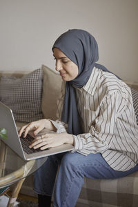 Young businesswoman typing on laptop while working from home in living room