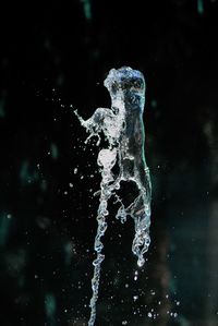 Close-up of drop falling on water against black background