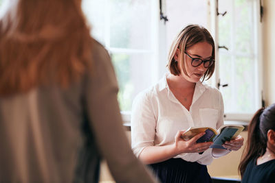 Young woman reading book in language classroom