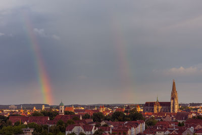 Rainbow over city buildings against sky