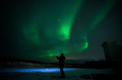 Rear view of man standing on beach against sky at night