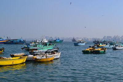 Boats moored in sea against clear sky