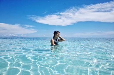 Full length portrait of smiling woman in sea against sky