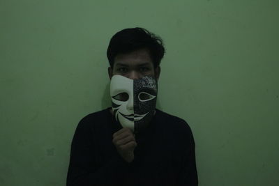 Portrait of young man wearing mask against wall