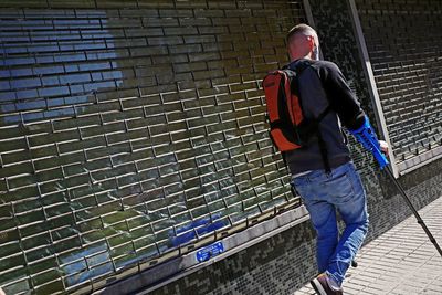 Rear view of man walking against wall