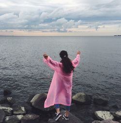 Rear view of woman standing in sea against sky