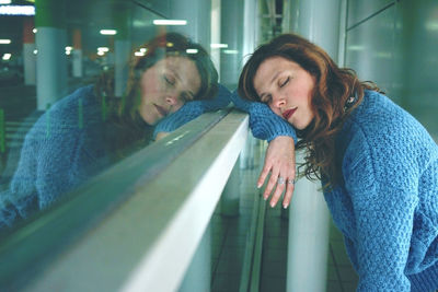 Side view of mid adult woman sleeping on window in parking lot