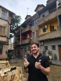 Low angle view of man smiling and holding a wine glass