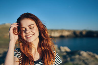 Portrait of smiling young woman against sky