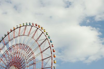 Low angle view of ferris wheel against cloudy sky