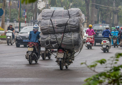 Rear view of people riding bicycle on road