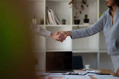 Midsection of businesswoman shaking hand at office