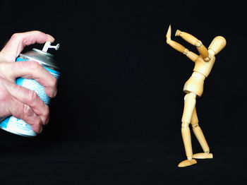 Close-up of hand holding cigarette against black background