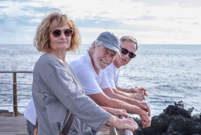 Portrait of smiling friends standing at beach