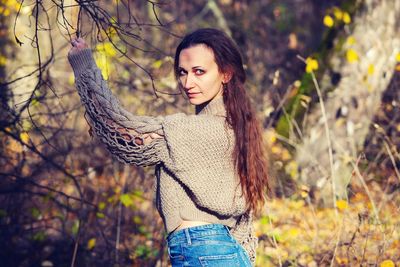 Young woman standing against trees