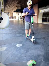 Full length of man holding skateboard standing on tiled floor