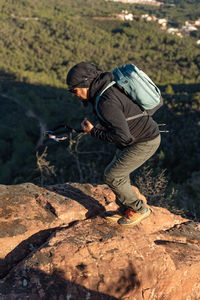 Middle-aged man climbs the mountain in the garraf natural park, supported by hiking poles.