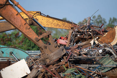 Excavator magnet lifting steel scraps from recycling materials pile at scrap yard in recycling