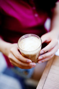 Midsection of woman holding coffee at table