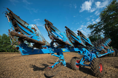 Damaged agricultural machinery on field against sky