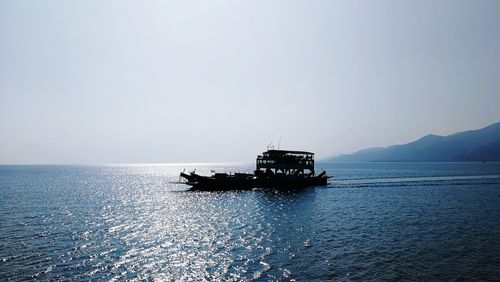 Boat sailing on sea against clear sky