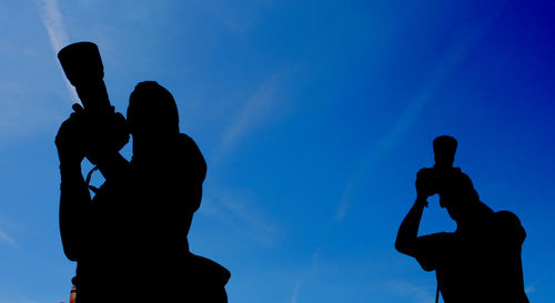 Low angle view of silhouette man photographing against sky